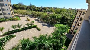 A parking lot with a few palm trees, surrounded by buildings and greenery.