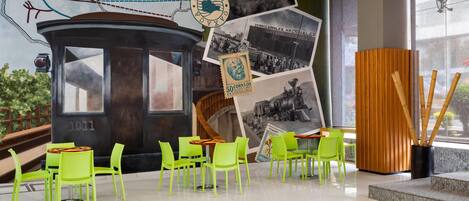 A modern interior with a vintage tram, green chairs, and a mural with historical photos.