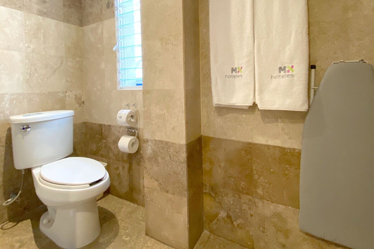 A bathroom with a toilet, a towel rack with towels, and a shower area.