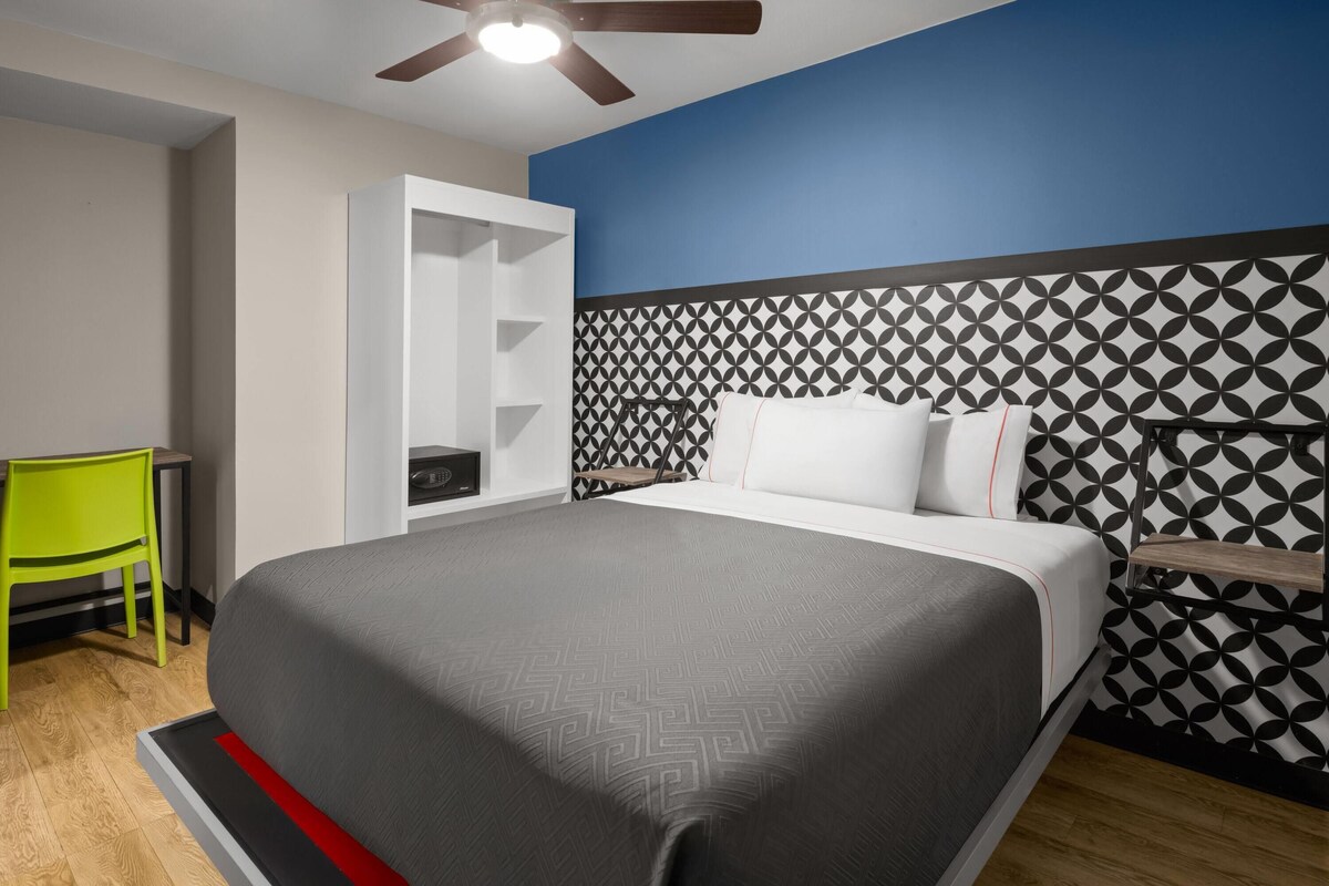 Quarto de hotel com cama, escrivaninha e uma cadeira.