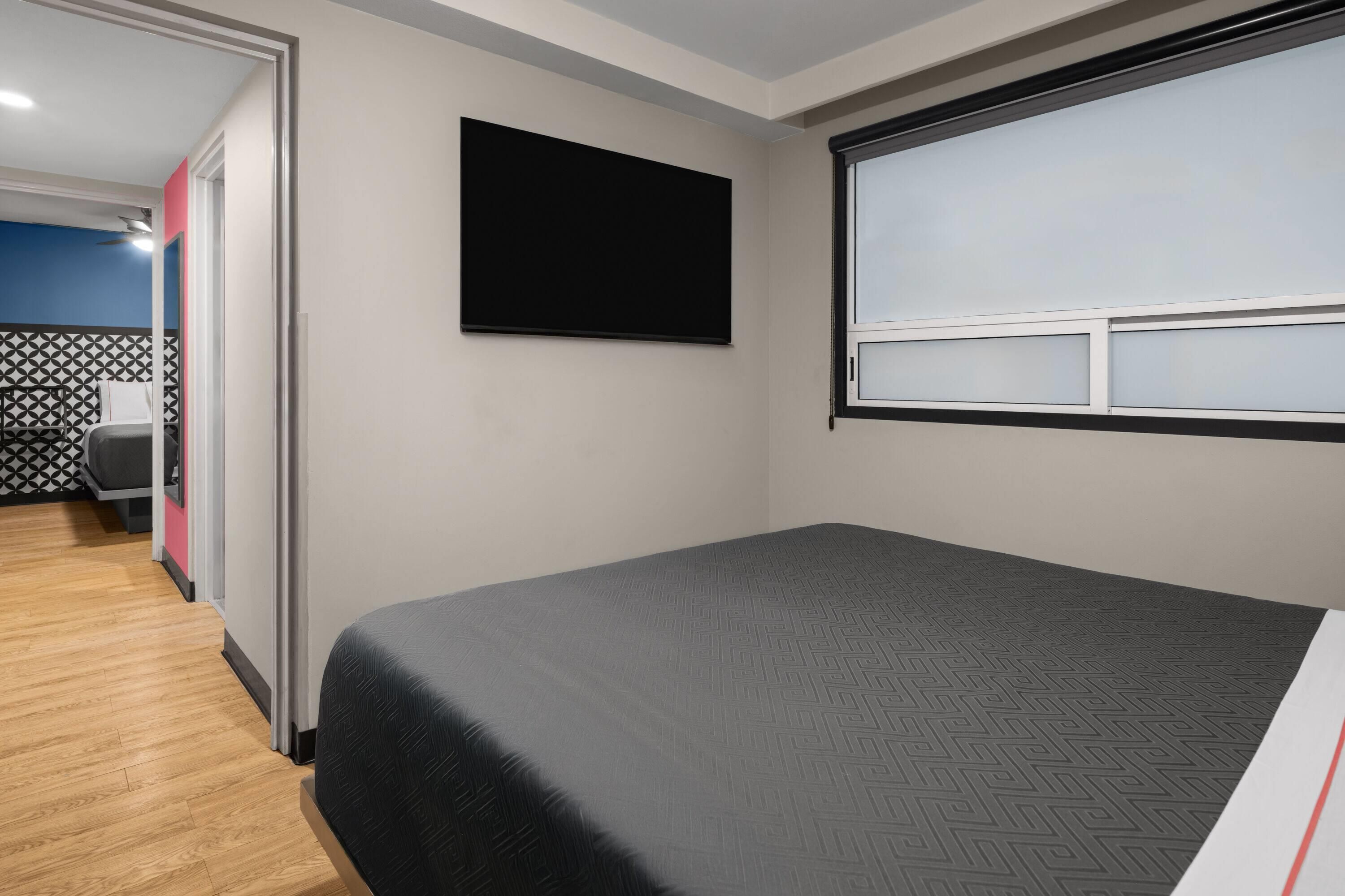 Una camera d'hotel con un letto, una TV a parete e una finestra con vista.