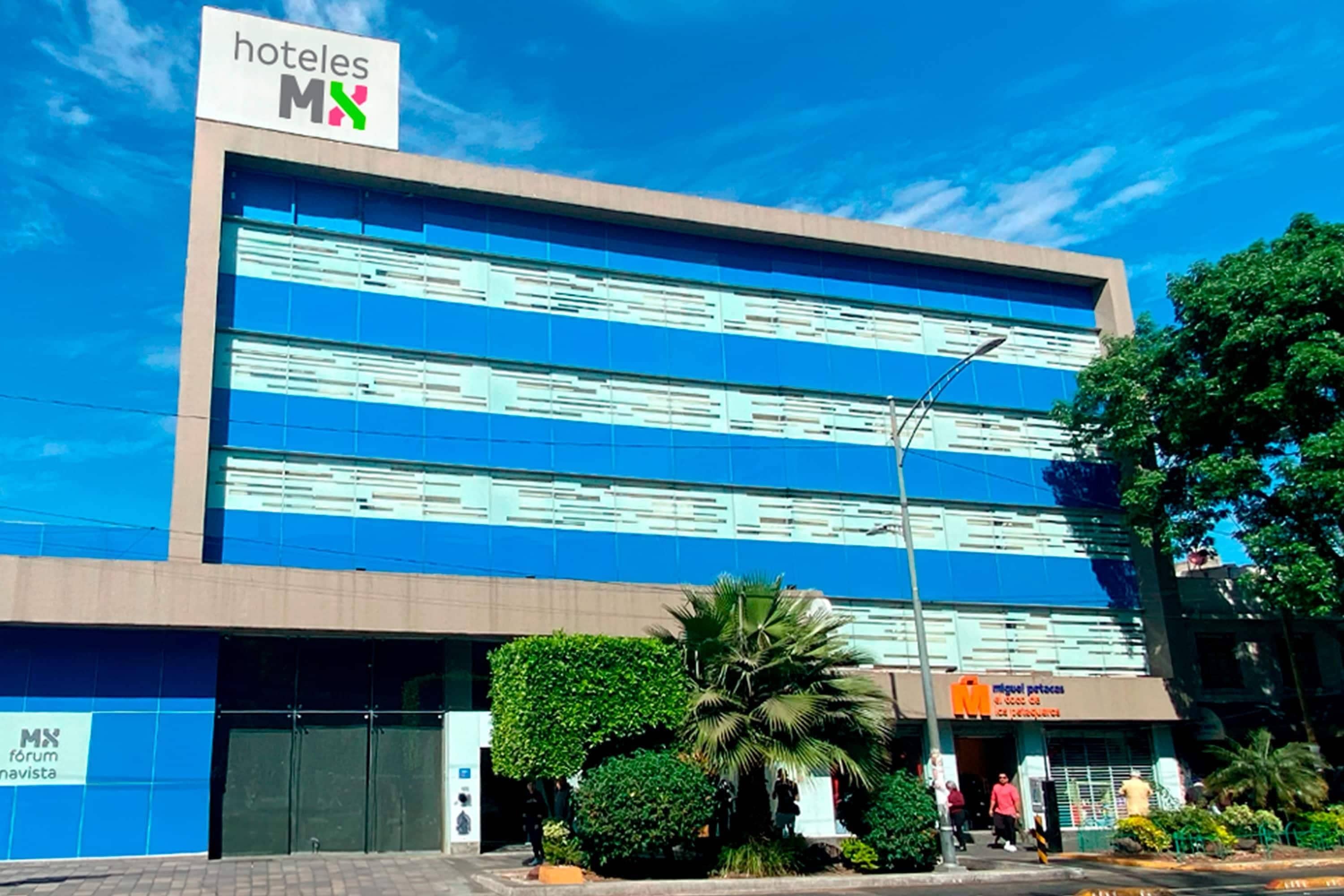 A hotel building with a sign 'hoteles MX' and a storefront with 'miguel potros' signage.