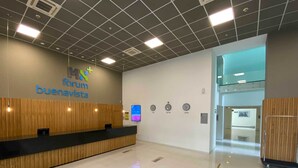 A reception area with a wooden reception desk, a sign reading "MX Forum Buenosavita", and clocks indicating different time zones. - Hotel MX forum buenavista CDMX, Trademark by Wyndham (Mexico City)