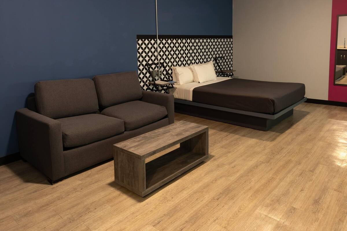 Ein modernes Zimmer mit einer Couch, einem Bett und einem Holztisch.