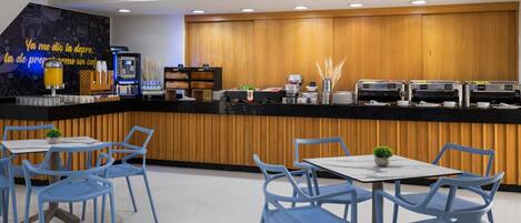 A cafe with a wooden counter, blue chairs, and a coffee machine.