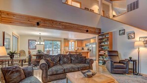 A spacious living area with a high ceiling, a sofa set, a coffee table, and a bookshelf. - Pet friendly, hot tub, ping pong (Sunriver)