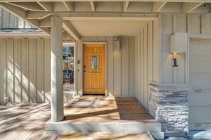 A wooden front porch with a door, a stone accent wall, and a mailbox.