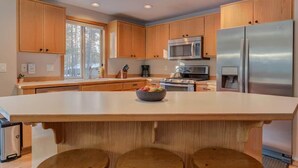 A modern kitchen with wooden cabinets, stainless steel appliances, and a central island. - Pet friendly, hot tub, ping pong (Sunriver)