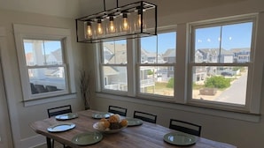Comedor con mesa de madera dispuesta para seis, ventanas amplias y vista a una zona residencial.