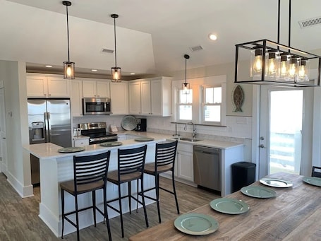 A modern kitchen with white cabinets, stainless steel appliances, and a central island with bar stools.