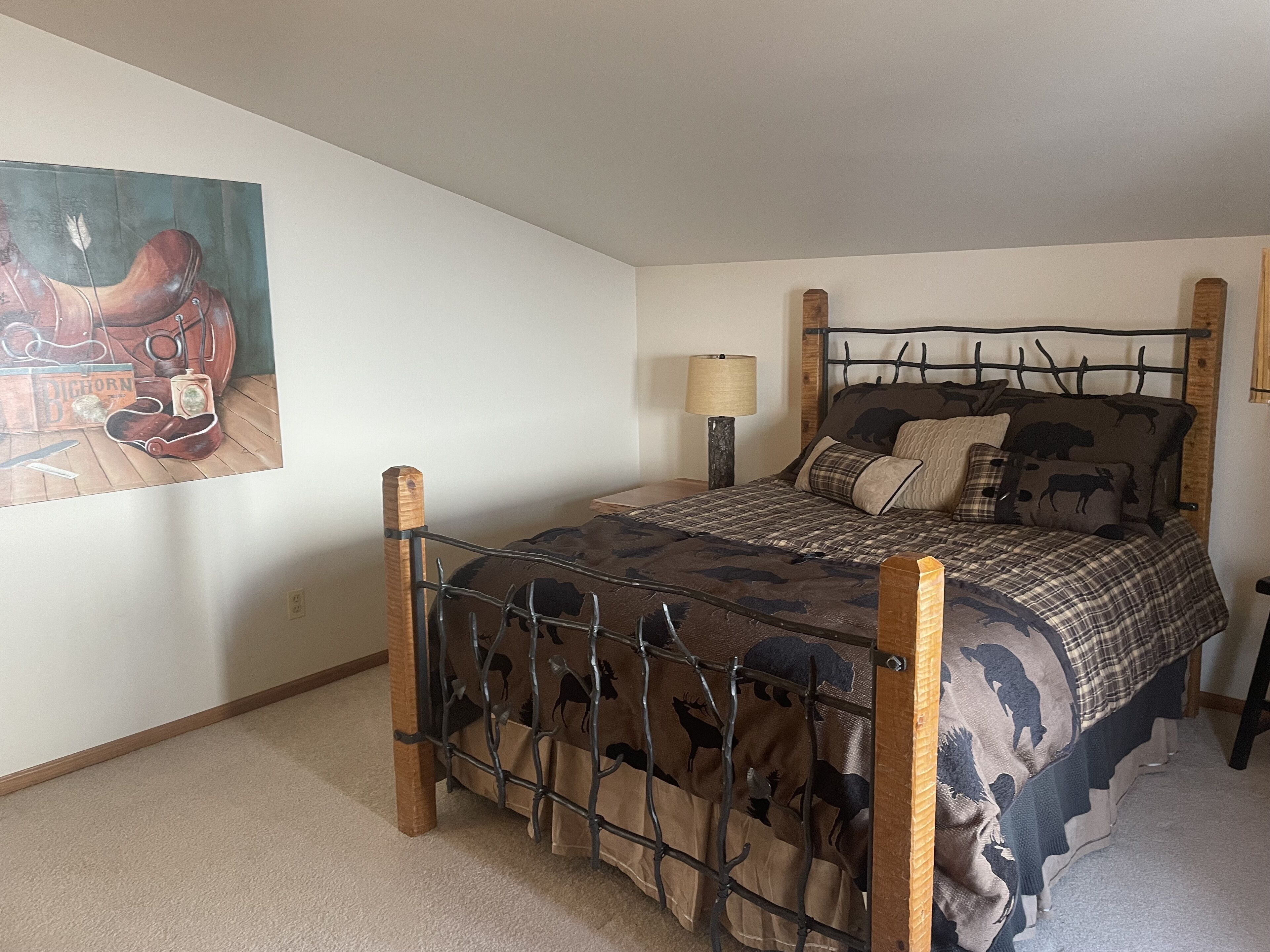 A bedroom with a bed, a lamp, and a painting on the wall.