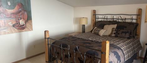 A bedroom with a bed, a lamp, and a painting on the wall.