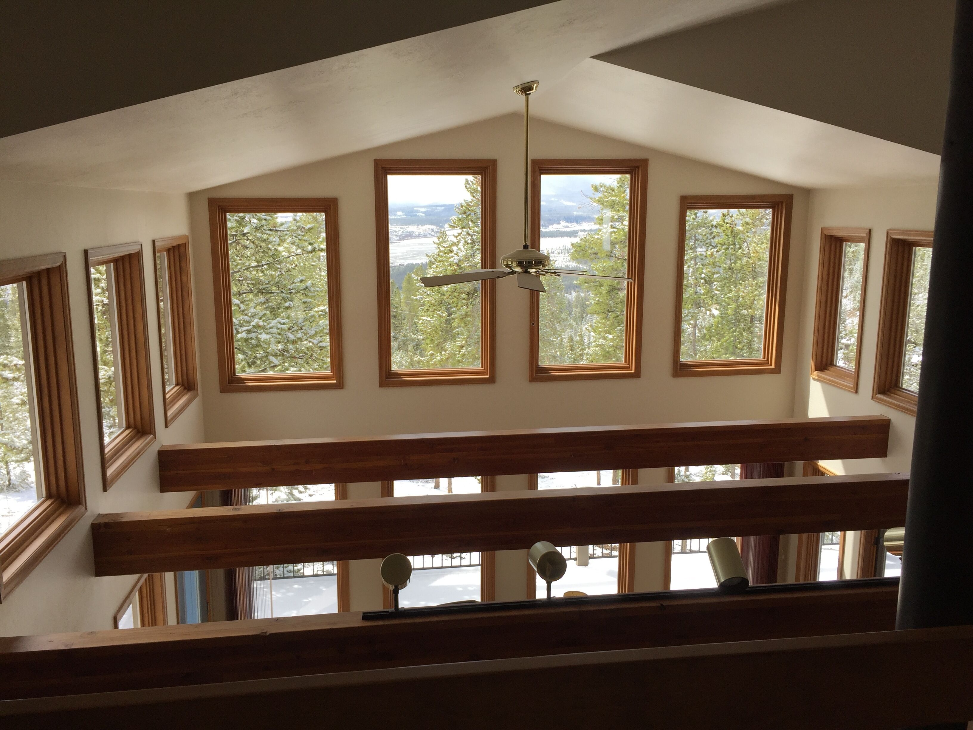 A high-ceilinged room with multiple windows offering views of a snowy landscape.
