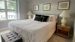 A bedroom with a bed, a ceiling fan, a window, and framed pictures on the wall. - Sun Filled Townhome w/Pool, 5' to beach, walk to bars/restos, luxury bath/shower (Marco Island)