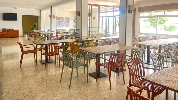 A spacious indoor dining area with multiple tables and chairs, large windows allowing natural light, and a flat-screen TV mounted on the wall. - Bluesea Costa Norte (Sanxenxo)