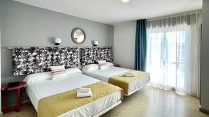 A hotel room with two beds, a mirror, a small table, and a window with curtains. - Bluesea Costa Norte (Sanxenxo)
