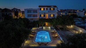 Une piscine avec des chaises longues et un escalier menant à un bâtiment.