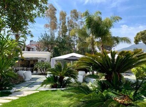 A lush garden with palm trees and a white gazebo. - Relais Corte Degli Aragonesi (Ischia)