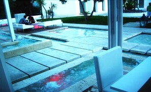A modern outdoor seating area with white benches and a water feature. - Relais Corte Degli Aragonesi (Ischia)
