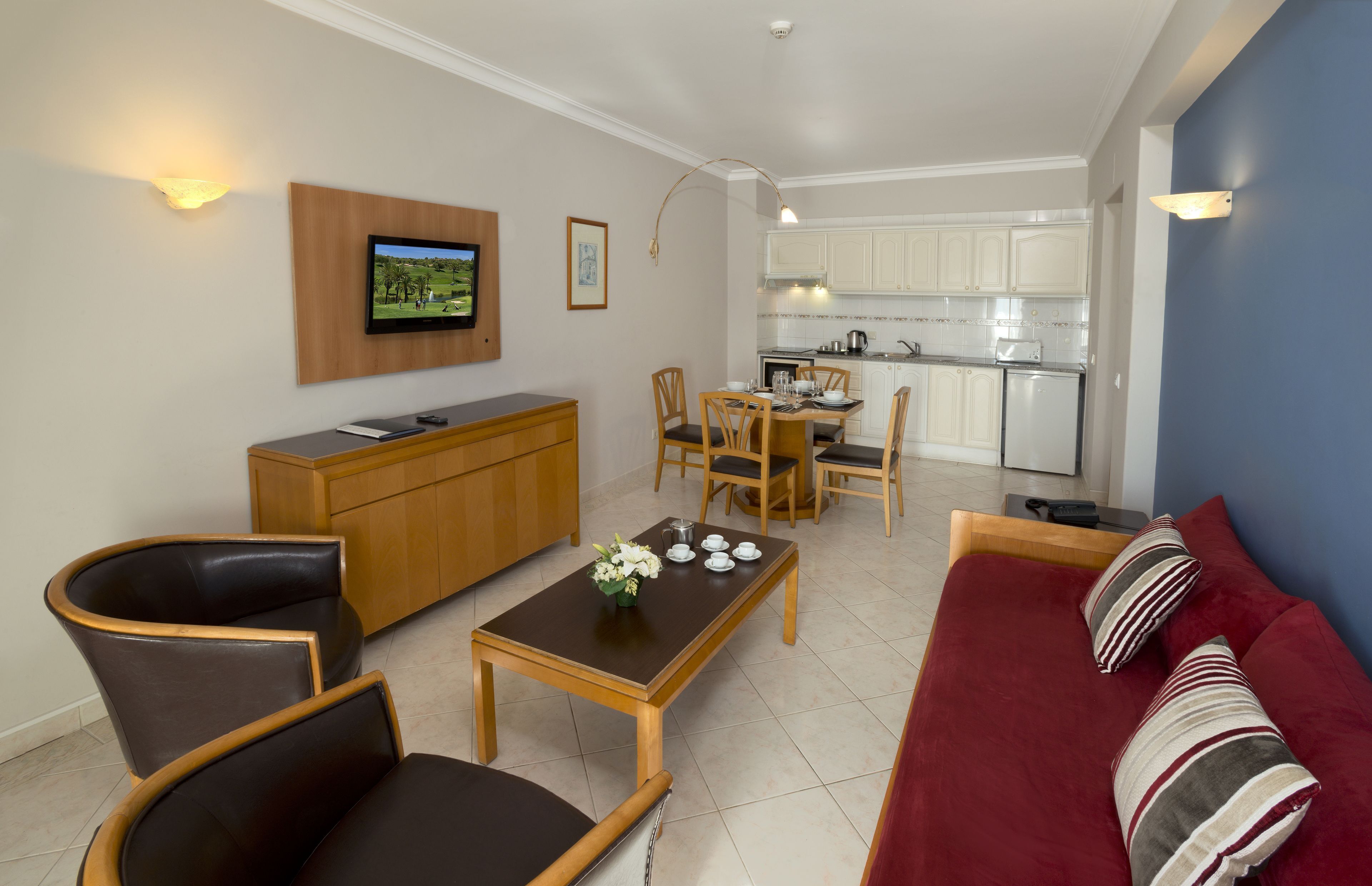 Uma sala de estar com televisão, móveis de madeira, área de jantar e cozinha.