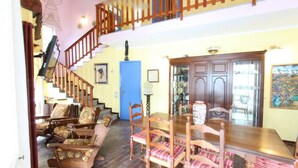 Un amplio salón con una escalera de madera, una mesa de comedor con sillas y una puerta azul.