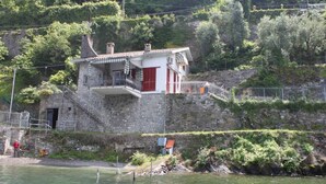 Un edificio de piedra con balcón, cerca de una masa de agua.
