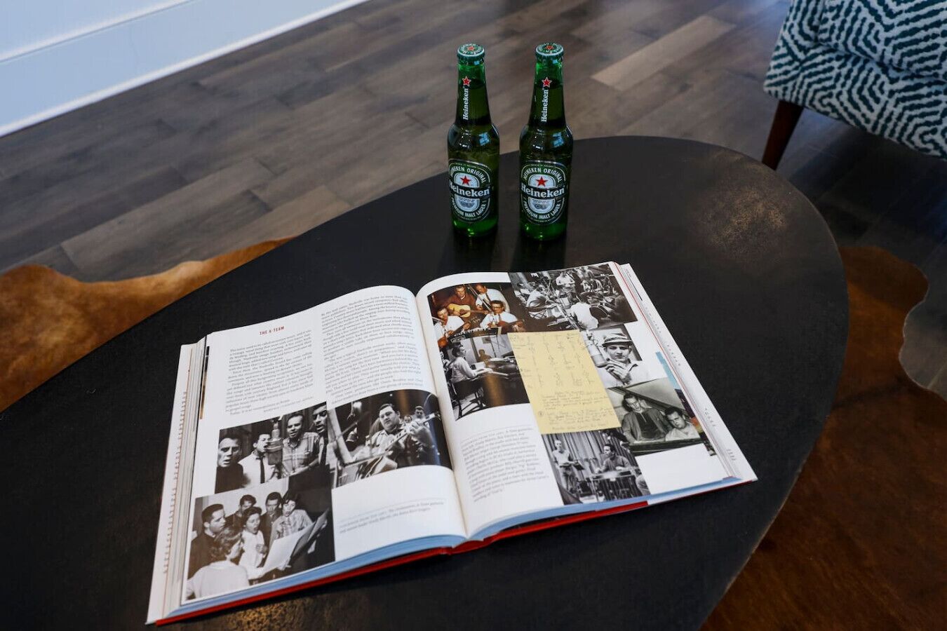 Ein offenes Buch mit Fotos und Text auf einem runden Tisch, dazu zwei Heineken Bierflaschen.
