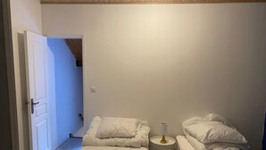 Ein Schlafzimmer mit zwei Betten, einem Nachttisch und einer Tür zu einem anderen Raum.