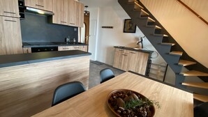 Eine moderne Küche mit Holzschränken, einer schwarzen Arbeitsplatte und einem Essbereich mit Tisch und Stühlen.