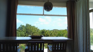 Une pièce dotée d’une grande fenêtre, d’une table avec des chaises et d’un luminaire suspendu.