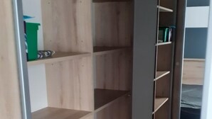 A walk-in closet with multiple wooden shelves and a metal rod. - Mobile home from 2022 at La Carabasse campsite (Vias)