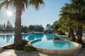 Una piscina con palmeras y un pabellón en el fondo.