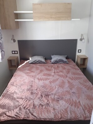 Een slaapkamer met een bed, twee nachtkastjes, een hoofdbord en wandplanken.