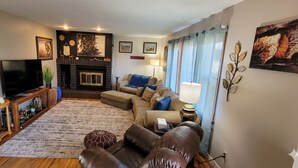 A living room with a television, sofa, coffee table, fireplace, and decorative wall art.