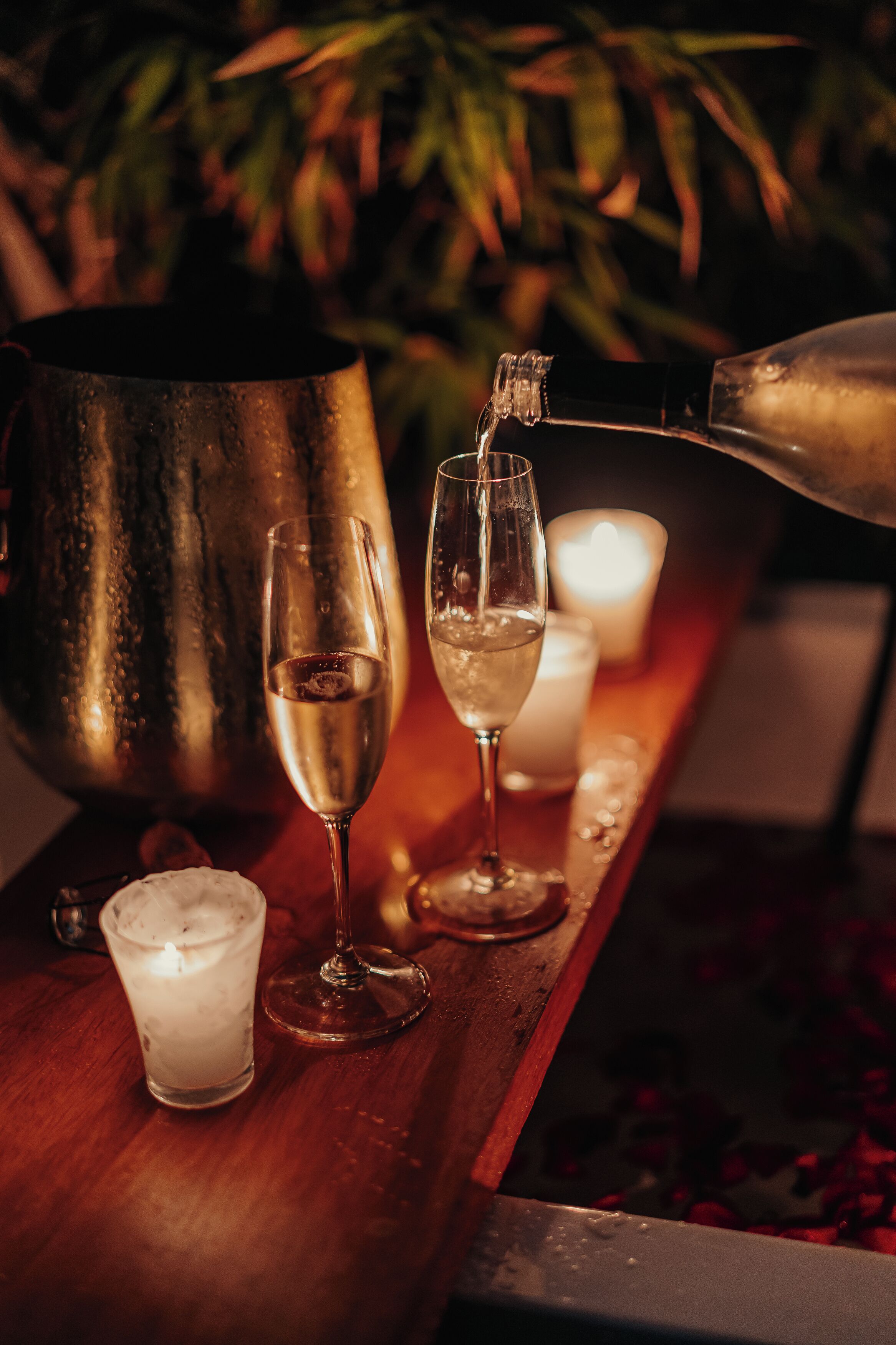 A bar setting with glasses of a clear liquid, a candle, and a large metal container.