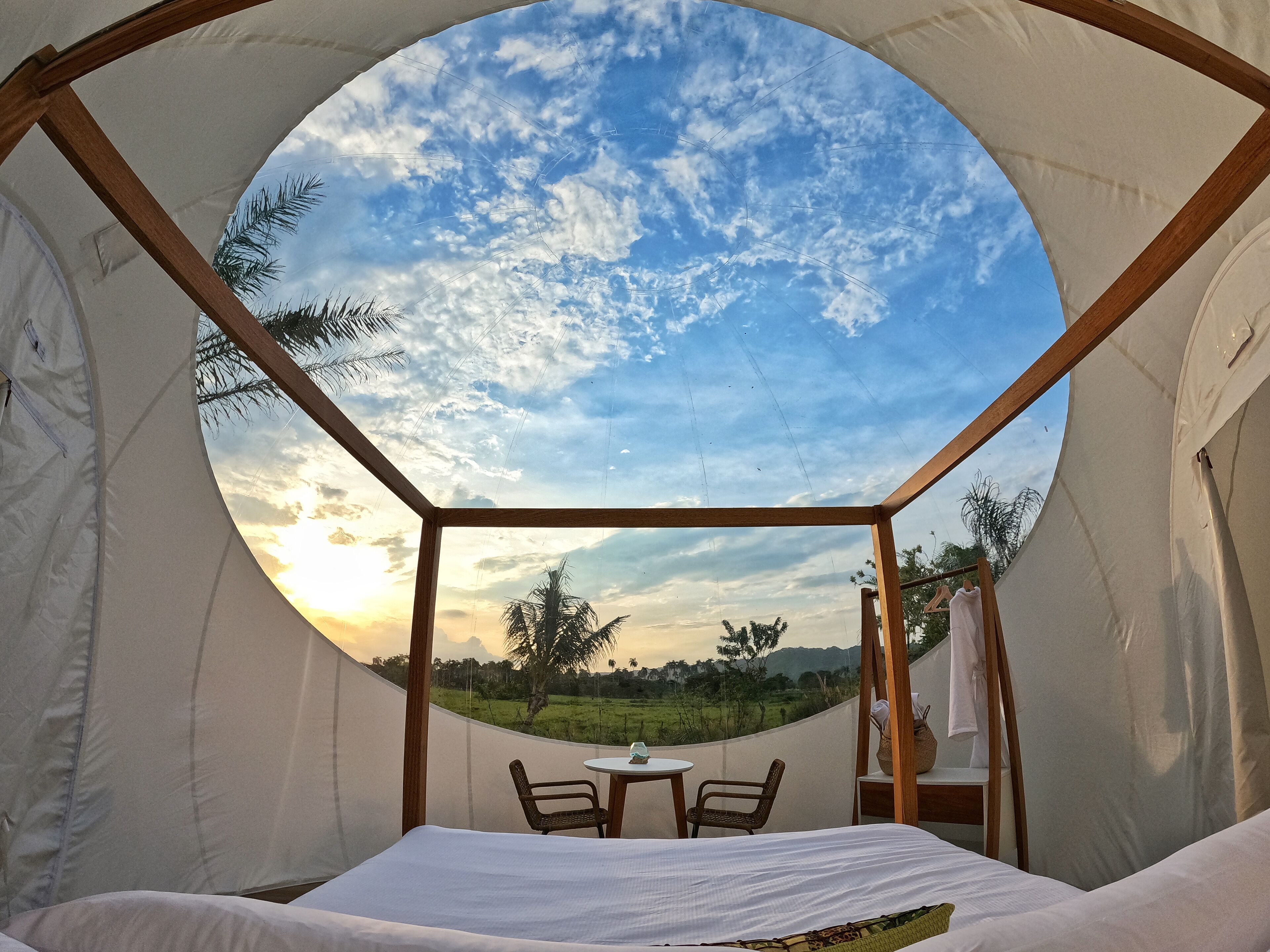 Een ronde tent met een bed, een tafel en twee stoelen.