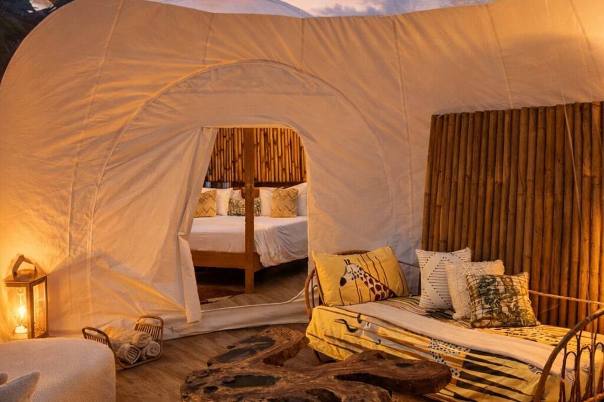 Een koepeltent met een bed, een bank en een houten tafel.