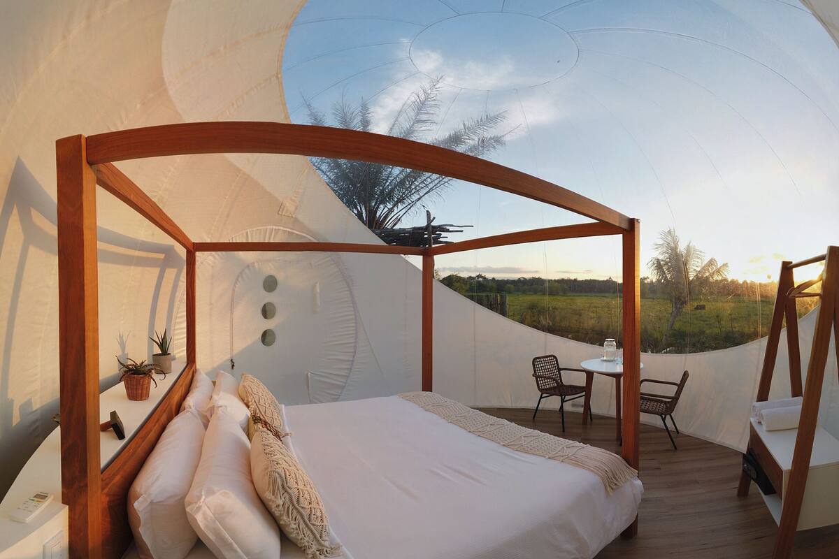 Een gezellige slaapkamer met een hemelbed, een klein tafeltje en stoelen, met uitzicht op een grasveld.