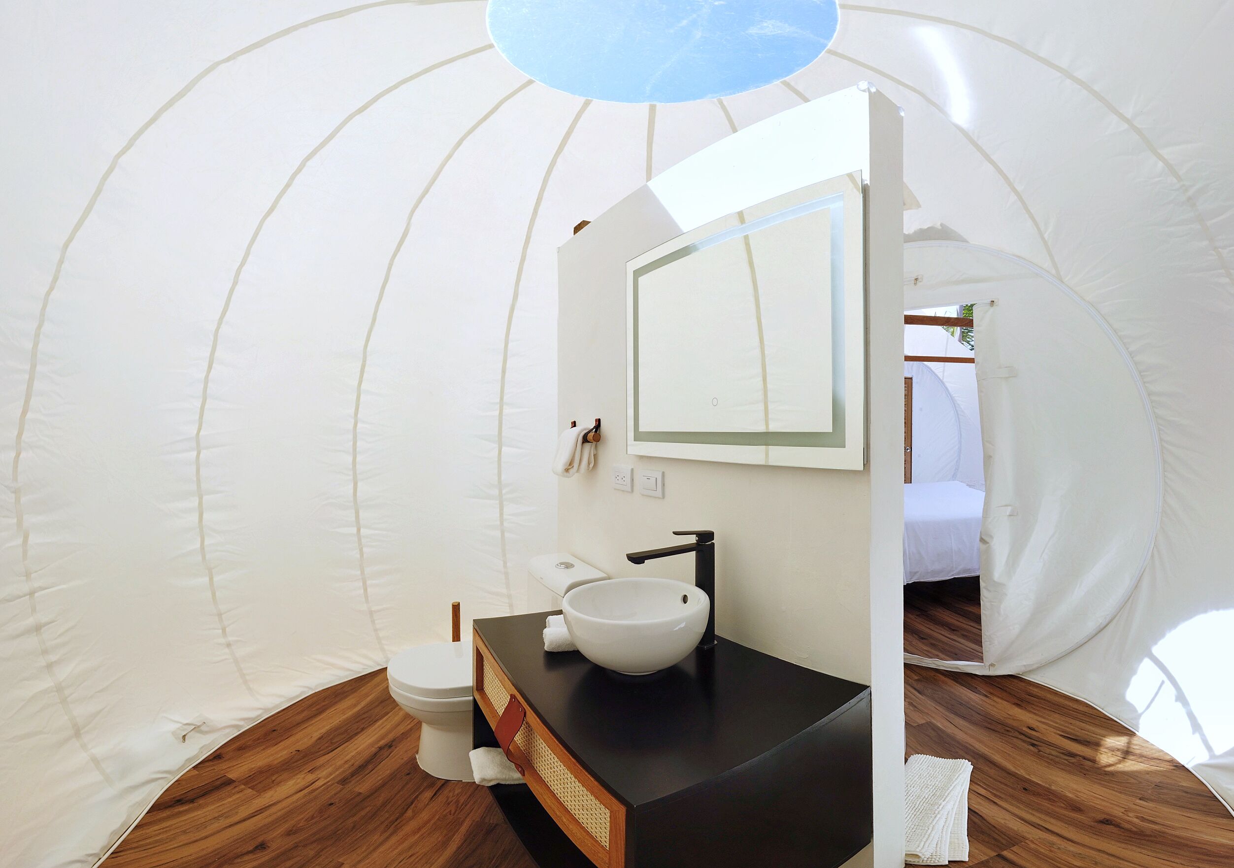 A compact, modern bathroom with a white sink, black countertop, and a large mirror.