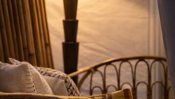 A room with a bed, a nightstand with a lamp, and a wicker chair.