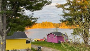 A lakeside cabin with a dock, surrounded by trees and a clear view of the lake. - Lakefront Pink Cottage (Northwood)