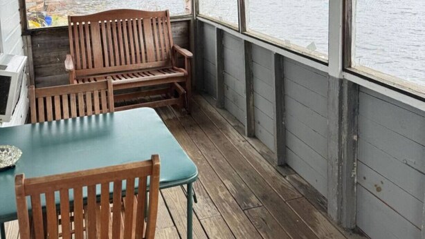A covered outdoor area with a wooden bench, a table, and a view of a lake. - Lakefront Pink Cottage (Northwood)