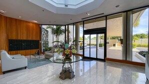 Um lobby moderno com uma mesa de vidro, um sofá e uma parede de exposição.