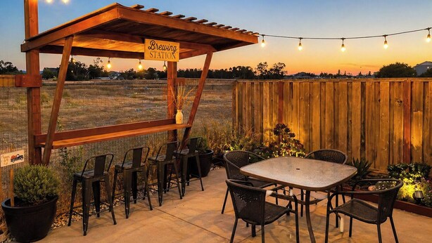 An outdoor patio with a pergola labeled 'Brewing Station,' surrounded by chairs and a table, with string lights overhead. - Russian River Brew-cation Home (Santa Rosa)