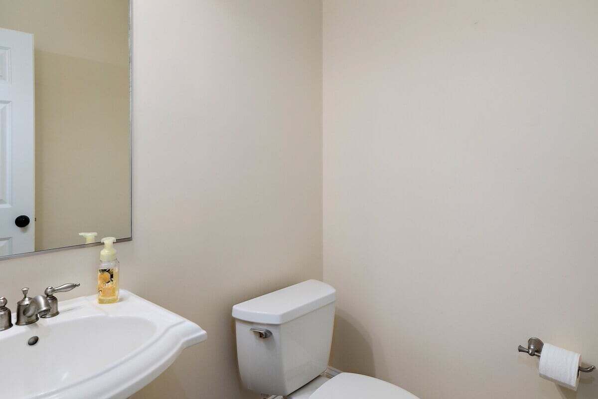 A bathroom with a white sink, a toilet, and a mirror.