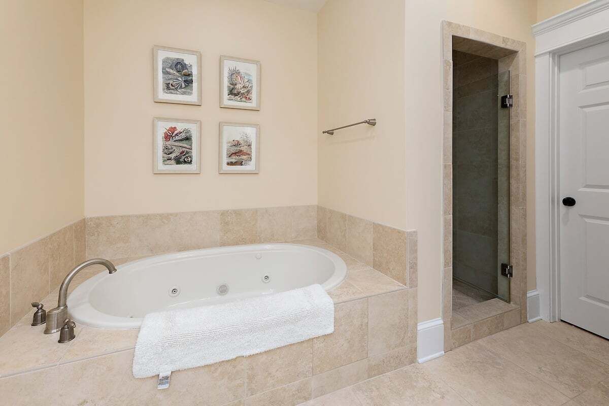 A bathroom with a freestanding bathtub, a towel rack, and four framed pictures on the wall.