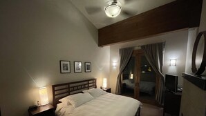 A hotel room with a large bed, bedside lamps, a desk with a lamp, a television, and a mirror. - Luxury ski-in townhome in Solitude Resort (Salt Lake City)