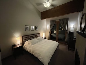 A hotel room with a large bed, bedside lamps, a desk with a lamp, a television, and a mirror.