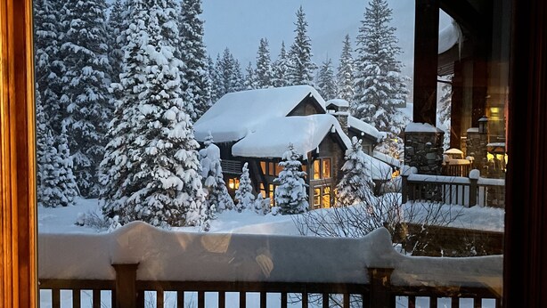 A snow-covered lodge with a wooden deck and a stone facade. - Luxury ski-in townhome in Solitude Resort (Salt Lake City)
