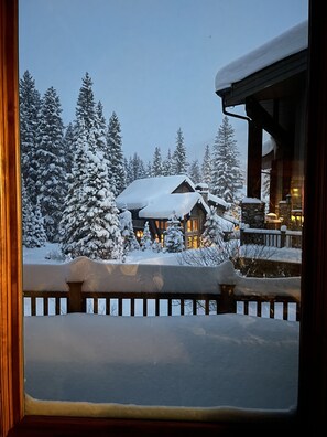 Een chalet bedekt met sneeuw, met een houten terras en een gevel van natuursteen.